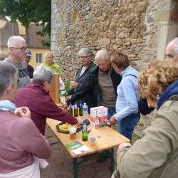 Groupe de personnes autour d&#039;une table en bois, en extérieur au pied d&#039;une construction ancienne en pierre, en train de boire et grignoter. On aperçoit plus loin une tour ronde d&#039;un bâtiment ancien.