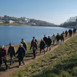 Randonneurs passant devant un étang sous un ciel bleu
