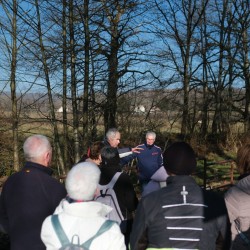 Randonneurs en pause écoutant les explications historiques du guide sur un pont