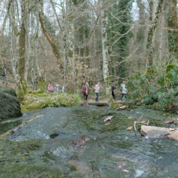 Au premier plan de l&#039;eau qui coule vers une cascade, au 2e plan (flou) des gens en contrebas qui marchent sur un chemin &amp;amp; ponton.