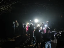 Des marcheurs à l'arrêt de nuit, ils sont équipés de lampes frontales qui permet de distinguer des personnes et des branches d'arbres.
