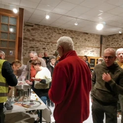Des gens se restaurent debout, d'autres servent à boire dans une pièce aux murs en pierre largement éclairée.