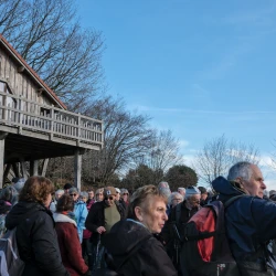 Regroupements de personnes devant une maison en bois en hauteur sur des poteaux