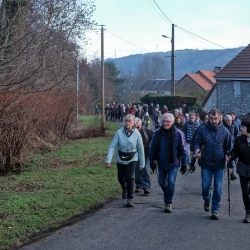 Marcheurs sur une route, d'un côté de la végétation, de l'autre des maisons